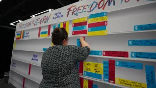A female NEA delegate stops by the Read Across America booth to places a note on the Freedom to Learn wall