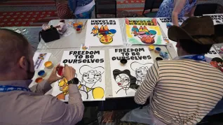 two attendees color in posters that say "freedom to be ourselves" at the Conference on Racial and Social Justice