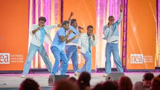 5 young black men dressed in blue perform on stage at the Conference on Racial and Social Justice