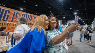 WNBA legend Helen Darling with an NEA RA delegate, taking a selfie, in front of the Read Across America display