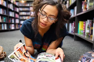 High school student reading graphic novel in the library