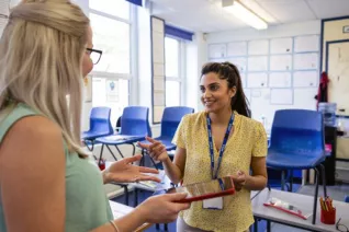 two teachers talking in an empty classroom