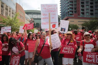 Women wearing red shirts, holding picket signs