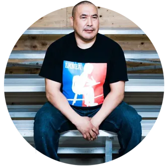 Man with short dark hair sitting on bleachers.