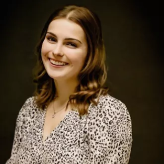 A woman smiling poses in front of a black back drop.
