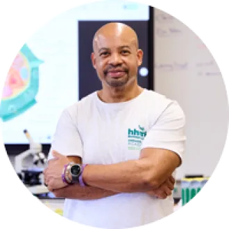 A man stands with his arms crossed with a slight smile looking directly at the camera.