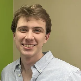 Headshot of a man with big smile, wearing a light-colored collard shirt.  