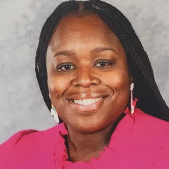 A woman in a pink top smiles brightly to camera.