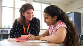 A young teacher works with a student in a classroom setting