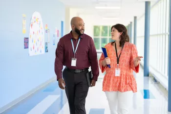 two educators walk down a school hallway