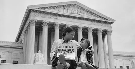Black mother and daughter hold newspaper announcing end to school segregation