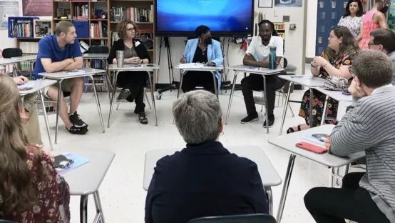 NEA President Becky Pringle and East Forsyth High School educators sit in desks in a circle in a classroom