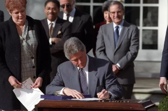 Photo of Bill Clinton signing legislation at desk