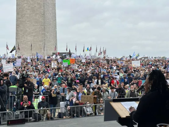 NEA President Becky Pringle stands on stage and addresses a large crowd in front the Washington Monument in DC