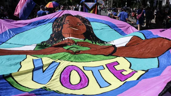 Close up for parachute banner that shows a young woman forming a heart with her hands above the word "VOTE."