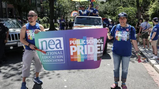 Two marchers flank an oversized Public School Pride banner