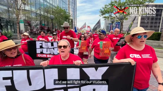 California Teachers Association member wearing red t-shirts walk in a No Kings demonstration carrying a sign that says to fully fund schools