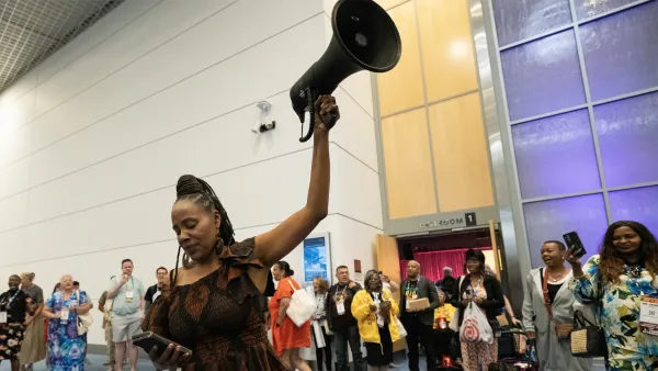 A woman holding a megaphone stands in the middle of a supportive crozwd. 