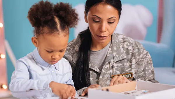 A mom wearing camo helps her child with school work