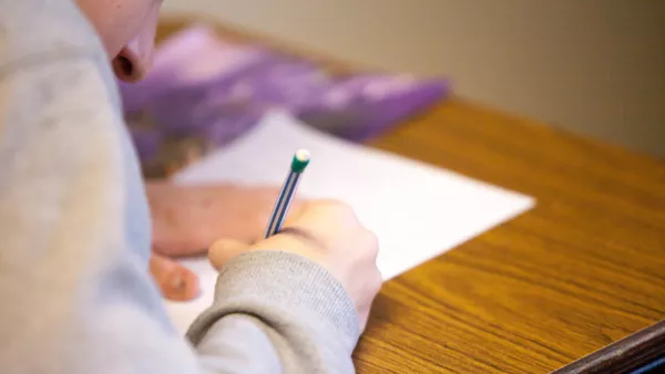 A behind-the-shoulder shot of a student taking an exam with a mechanical pencil.