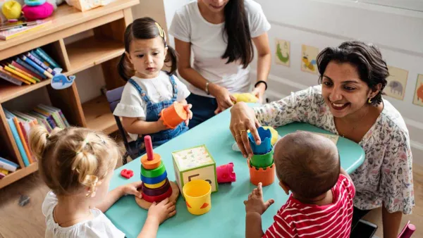 young, sidverse children play at a table with blocks and toys with two teachers 