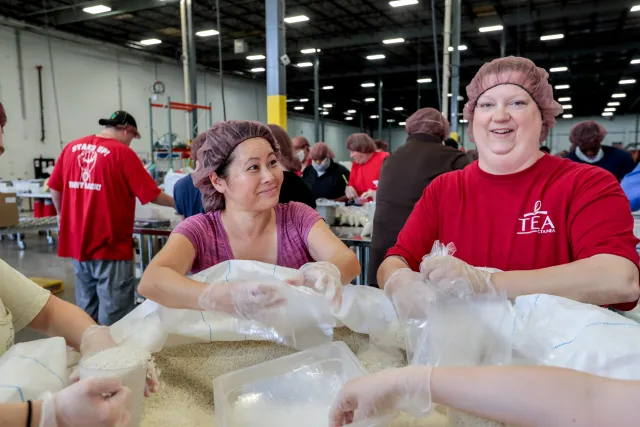 Two NEA members fill bags with food