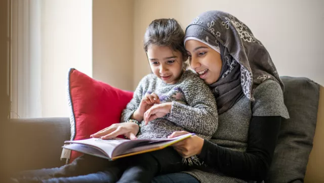 Sister in headscarf reads to younger sister