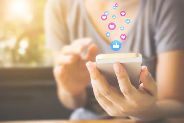 A woman uses her phone to post on Facebook