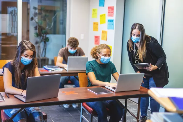 Students in masks using computers in classroom