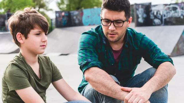 Father talking to son while sitting outside
