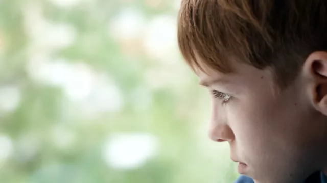 sad boy looking out a window