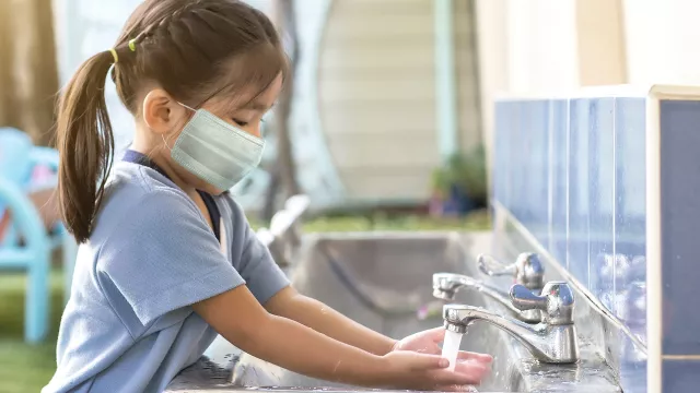 young student washing hand with mask on