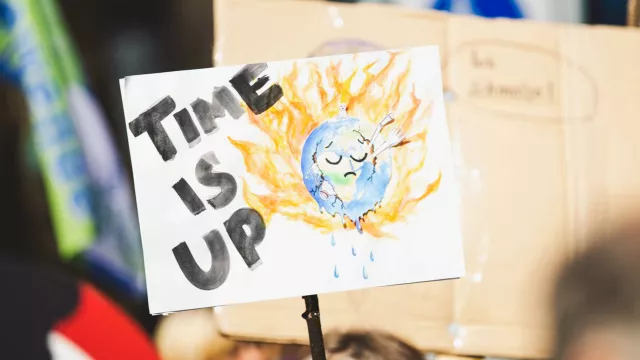 climate change protest sign that reads Time is Up with image of burning planet