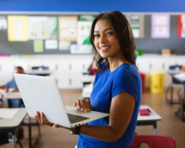 young female teacher with a laptopn in middle school classroom