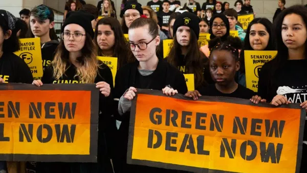 Student activists hold up signs reading, "Green New Deal Now"