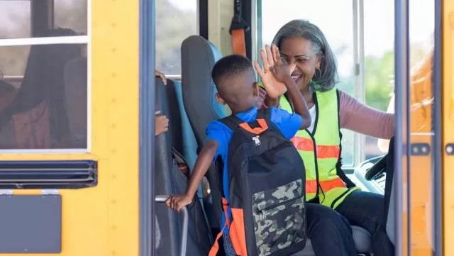 A school bus driver giving a student a high-five