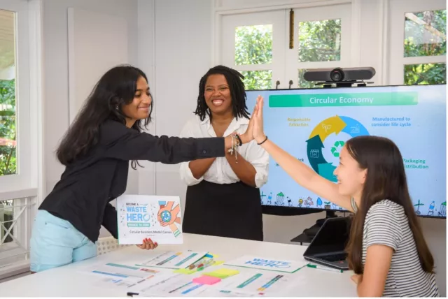 two students and moderator high five over their WasteHero project