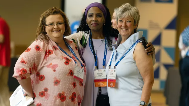 three women standing and posing for a photograph in a hotel lobby