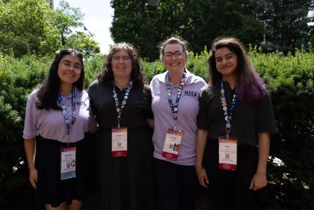 Four Aspiring Educators stand with their badges.
