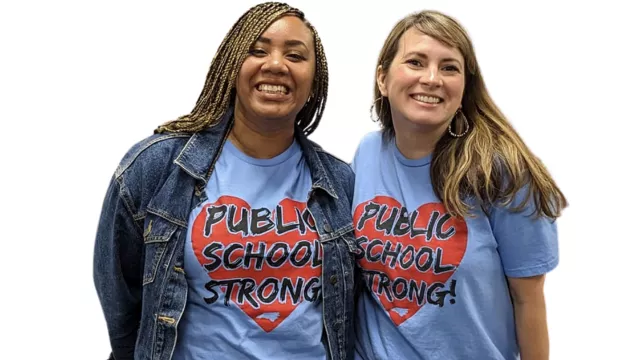 Two women wear blue t-shirts with the word Public Schools Strong and look into the camera