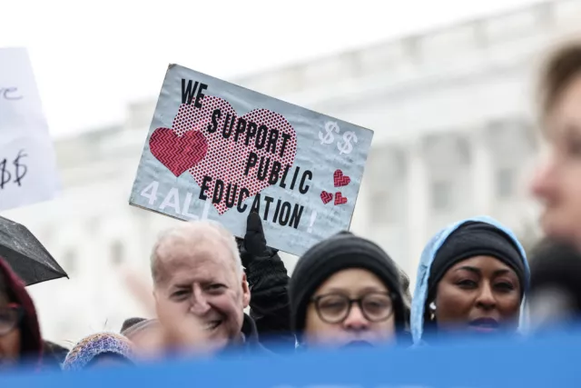 A crowd of people holding various signs about supporting public education.