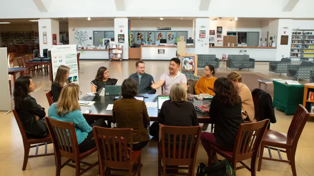 Educators sit around a table discussing important topics.