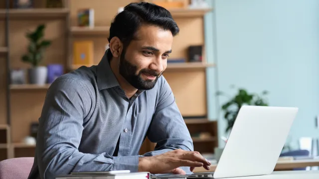 A man sits using a laptop.