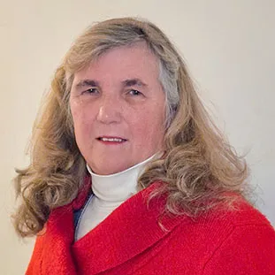 headshot of blonde-haired woman smiling and wearing an ivory turtleneck and a red jacket