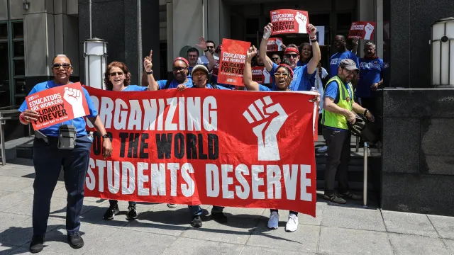 A group of NEA members with a banner that says "organizing for the world students deserve"