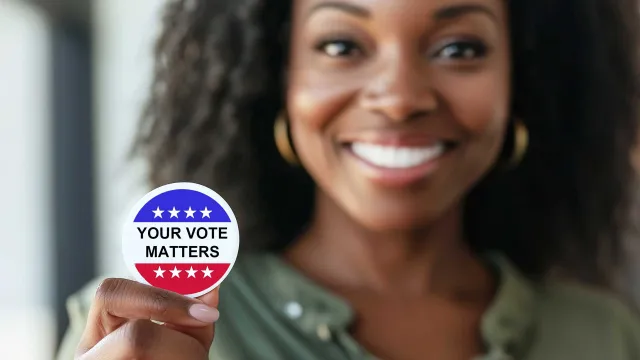 Black women smiling and holding a Your Vote Matters sticker.