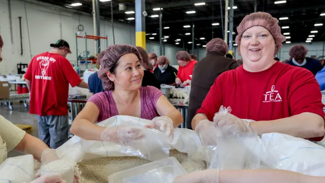 Two NEA members fill bags with food