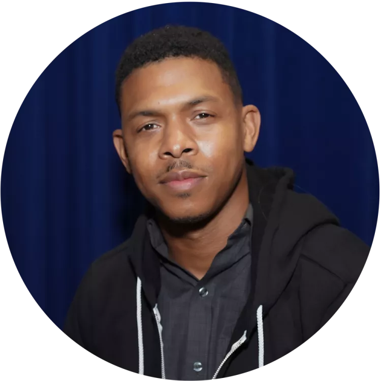 young black man educator in front of a blue curtain