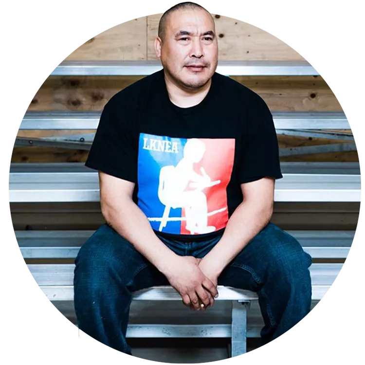 Man with short dark hair sitting on bleachers.