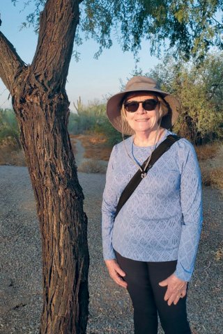 NEA-Retired member Katri Hakes in a hat and sunglasses, standing under a tree.